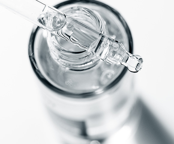 clear dropper above a glass bottle with liquid demonstrating skincare product 2 features for hydration and nourishment